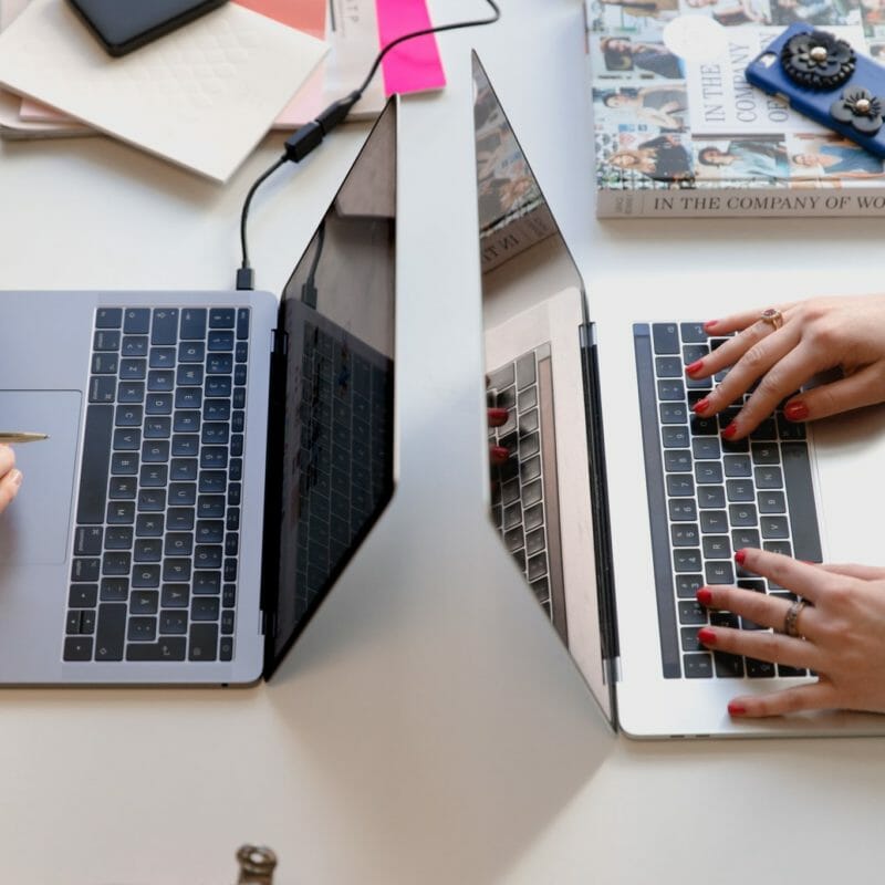 open laptops on desk, hands typing
